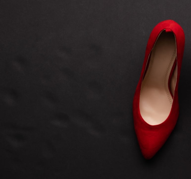 A studio shot of pair of red high heel shoes on black background. Flat lay.